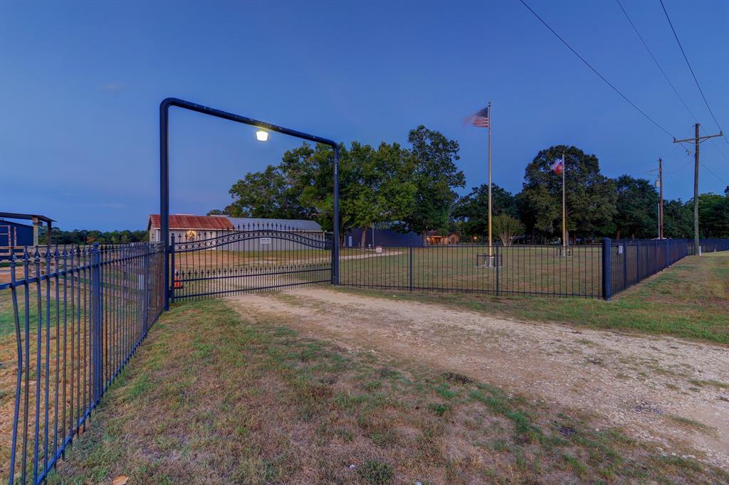 The private secondary entrance to the barn areas, which have 24 hour camera surveillance. The main home is located at the top right of the photo. Note the wonderful wrought iron fencing and gates. Welcome to this turnkey Farm of Dreams!!