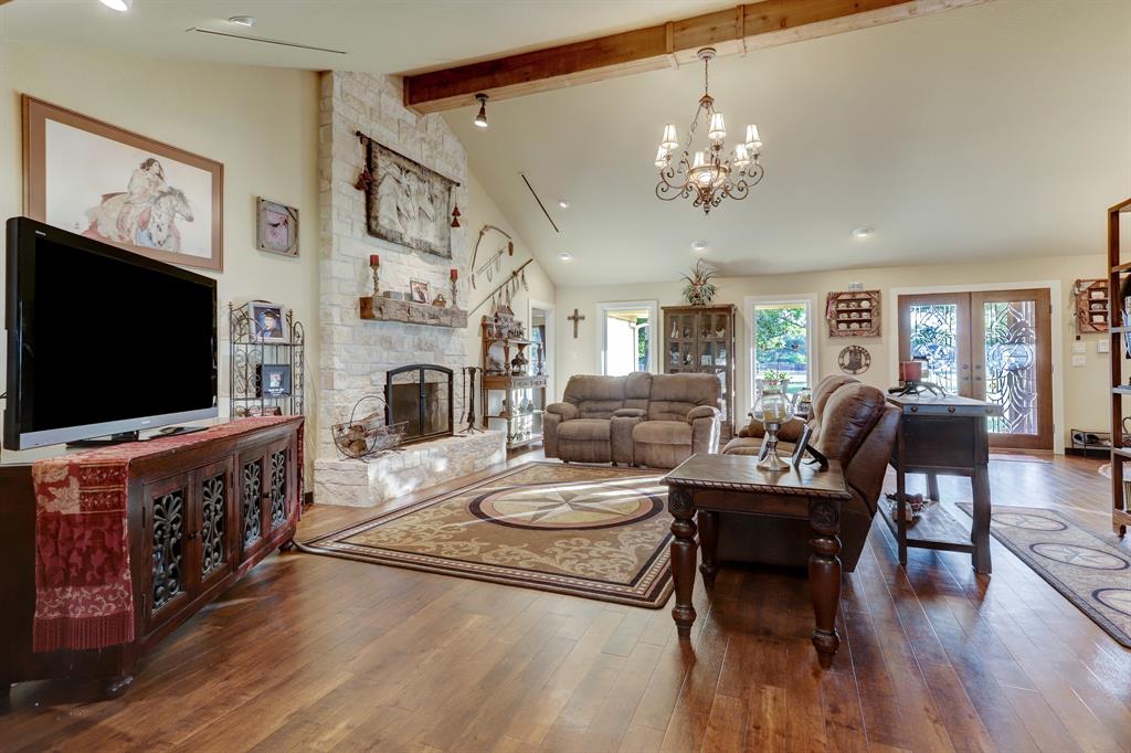 Spacious main living area with floor to ceiling windows, high ceiling, beautiful wood type flooring, and a warming fireplace with limestone surround.