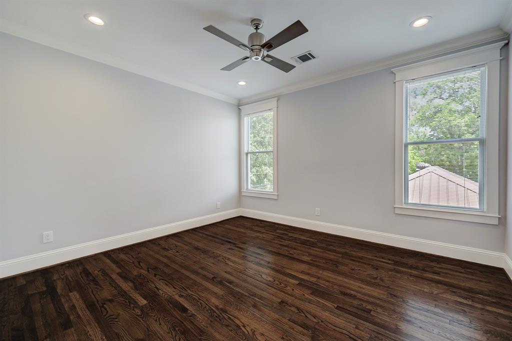 Large primary bedroom with ensuite bathroom. Notice the hardwood floors and crown molding throughout.