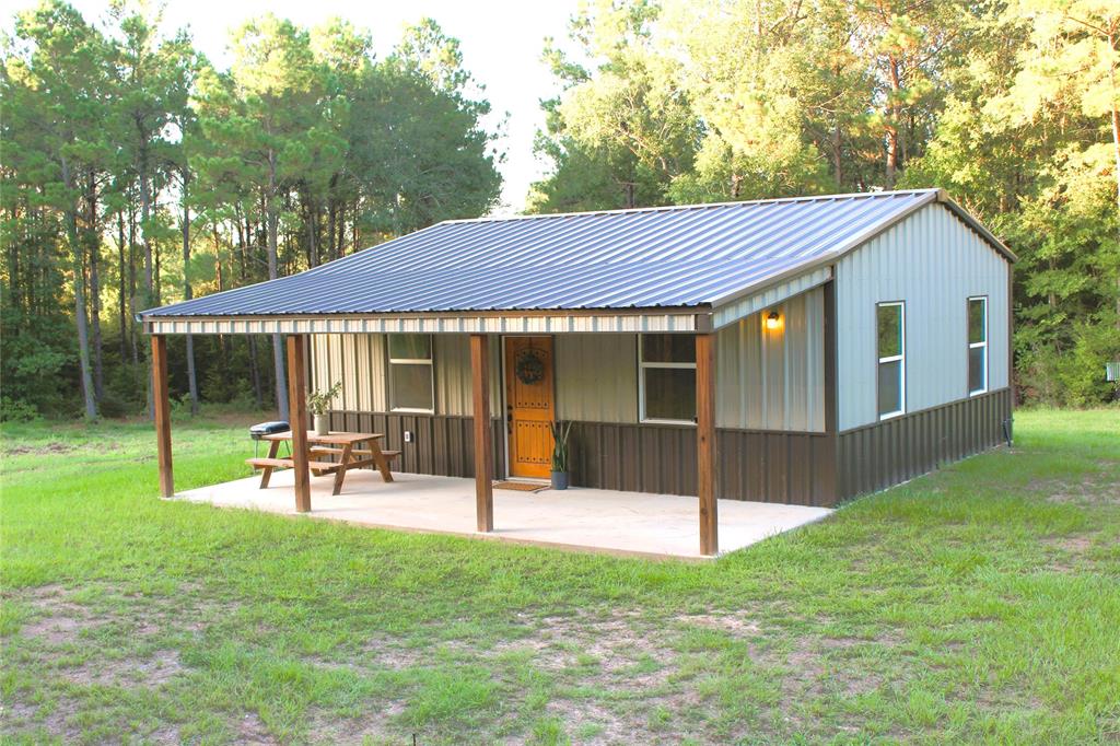 Honey stop the car!! Your dream camp site awaits you.  Don't miss this less is more, minimalist 720 sq ft, 2017 barndominium.  Situated on a 10 acre tract that runs from McGee creek to the top of the hill. This quaint cabin-esk home comes fully plumbed w/ bathroom, shower, sink & toilet, ready for water to be activated.  Washer & dryer connections ready for your stackable appliances. Electric wired with 2, 100 volt panels inside & outside, tankless water heater, septic installed.  Most materials to finish the inside engineered wood flooring, kitchen cabinets, walls, doors, etc.. will convey.   Your one room "cabin" is heated and cooled by a brand new efficiency MRCOOL split unit.   This property offers quiet, private seclusion and an opportunity for a restful hideaway, with proven hunting of deer & hogs, deer blind is included.  Additionally, there is a metal shed for storage, just in case you need a place to keep your boat as Lake Livingston is just 1 mile away. Call for more details!