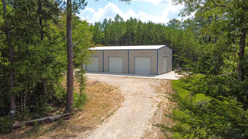 3.94 Acres with a pond and Large Insulated Metal Shop. The shop has 12 21,000 Lumen LED Bay Lights. It has it's own septic and public water. There are 5 bay doors on three sides of the building. Slab is over 5600 sq ft total with the building consisting of 3000 Sq Ft at 40X75 with 20' eaves. Can be used as a business, turned into a two story home, used as a transfer center for commercial route services, or whatever you can dream up. It is in a great location right between Huntsville & Livingston in the middle of the Sam Houston State Forest.