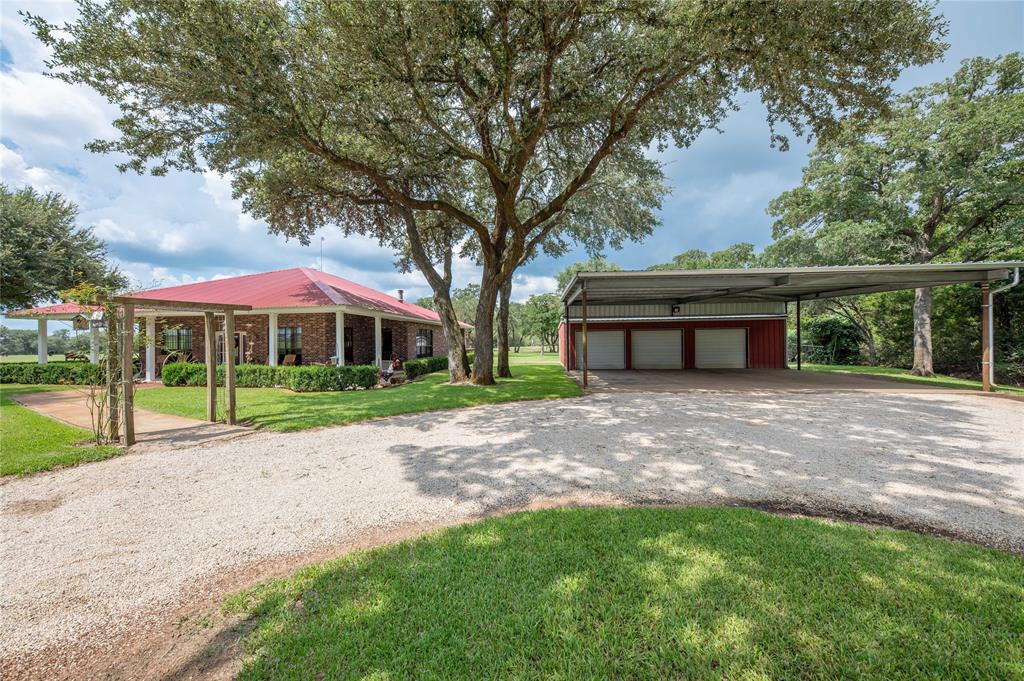 This awesome property has so much to offer to the entire family. The custom built home is nestled among mature oak trees, has wrap around porches and a stocked pond right beyond the back yard. A circular drive leads up to the 2696 SF, 3/2.5/3 home. There is an oversized home office for someone that has a career that allows them to work from home. The office can serve as a fourth bedroom if needed. A large pavilion was built for outdoor cooking and entertaining. Numerous storage sheds that will accommodate boats, utility vehicles and trailers. There are too many features to mention; an 8’ pool table that is located in the three car garage is one of several items that convey. Conveniently located within minutes of downtown Hallettsville, the local hospital, public and private schools. Call today for a tour of this magnificent country property.