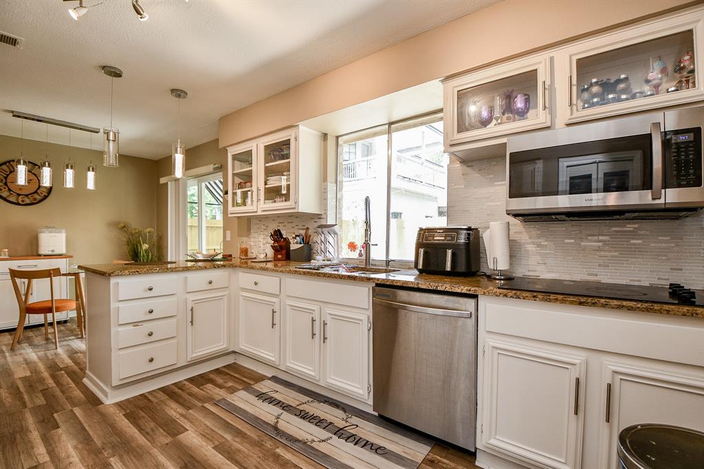 Sparkling and bright, your chef's kitchen/breakfast nook, has been gracefully updated with homey glass front wall cabinets (and plenty of them), new hardware, the lightest mocha toned, mosaic-like tile backsplash and stainless steel appliances.
