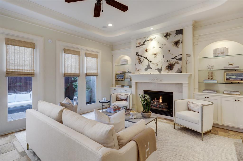 Beautiful Formal Living Room with Chiseled Travertine Floors, Gas Fireplace with Tile Surround, Built-In Cabinetry with Glass Shelving and French Doors that Lead to the Back Yard/Patio