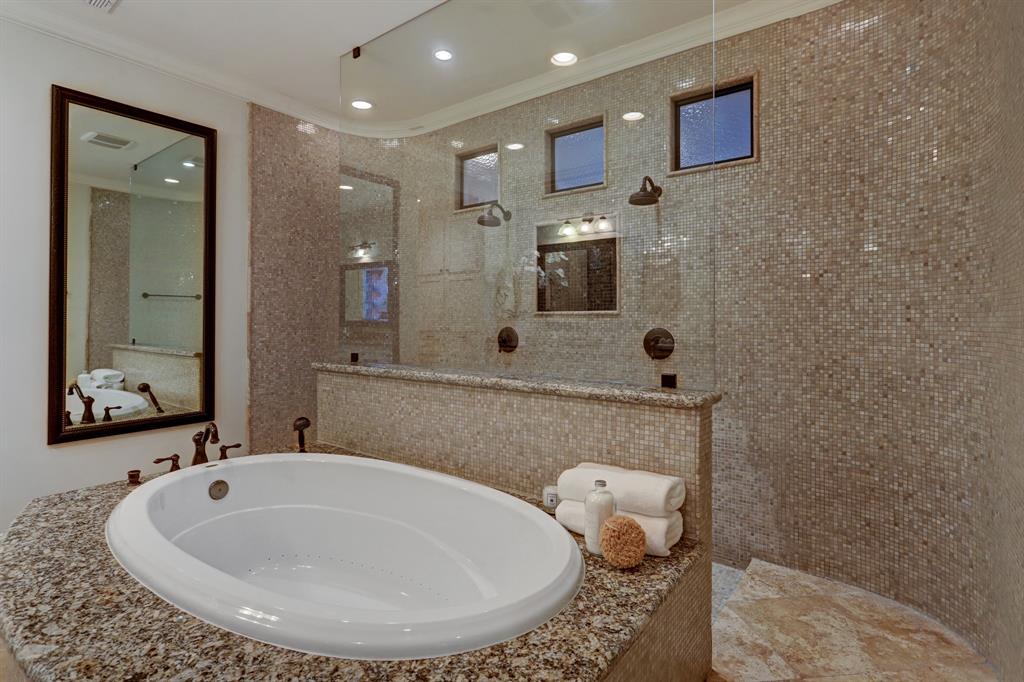 Master Bath with an Incredible Open Shower that Features a Wall of Mosaic Tiles and Dual Shower Heads. There is also a Large Soaking Tub with a Slab Granite Deck and Mosaic Tile Surround.