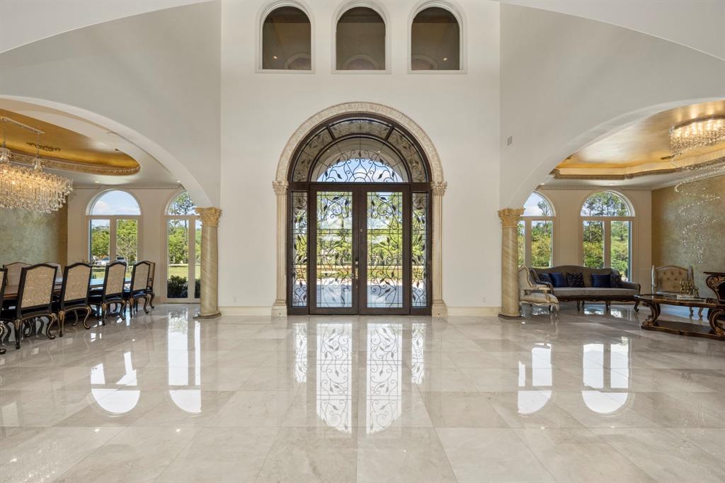 Custom front doors lead to large entry with beautiful marble floors