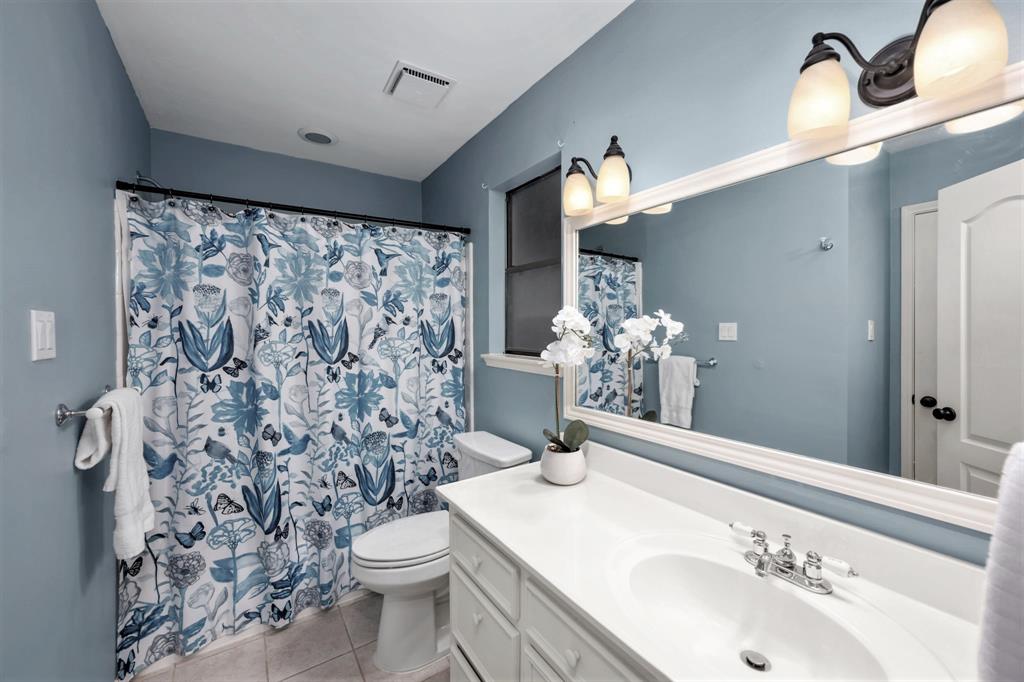 The third full bathroom upstairs is complete with a generously sized sink vanity, and an oversized framed mirror with vanity lighting. Open the curtain to yet another tub/shower combo.