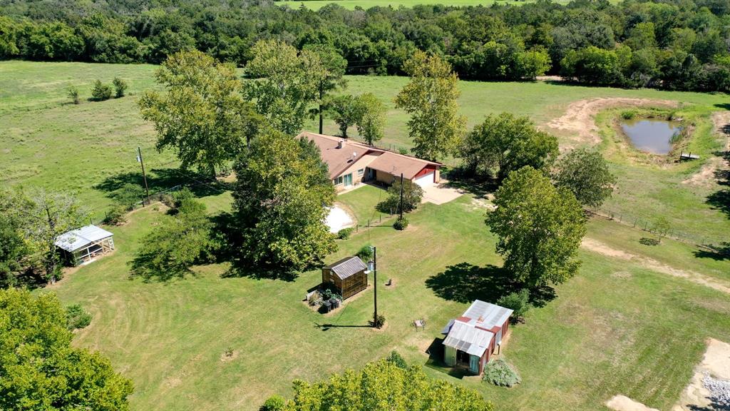 This gorgeous property consists of 12 Acres of Working Farm, 10 Acres Fenced & Cross Fenced, 2 Acres w/ Beautiful Brick Farm House, Milk Barn on slab 21x54, Pole Barn on slab 20x86, Large Hay Barn with Vaulted Ceilings and Cedar Beams 40x56, Stock Pond with Cat Fish and Pier, New Large covered Patio with Hot Tub recently added, Newly built Well Pump Shed with Full Bathroom,Outside sink for cleaning fish or Veggies, Mini Garage for your Golf Cart, Chicken Coop 16x16, 6 egg producing Chickens, 1 Duck, Two Acres with Fruit Trees: Fig, Pomegranite, Pecan, Pear, Plums, Peaches, Large fenceline of producing delicious domestic Blackberries, Flower Gardens on several acres, Large Greenhouse 8x12 with electricity and water next to Family Vegetable Garden. Property includes Current Ag Tax Exemption on 10 acres with 4 Brangus Mama Cows that produce, 1 sweet Horse & 1 fun and sweet Donkey. Lots of Storage! Working Compost Bins, Pool Pad with Decking, Plumbing - Electrical ready for your Pool!