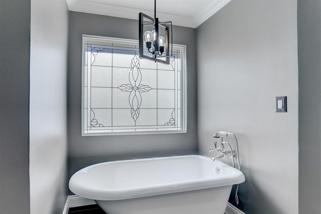 The clawfoot tub and tasteful, decorative window make spending time in the bath a worthwhile pursuit.