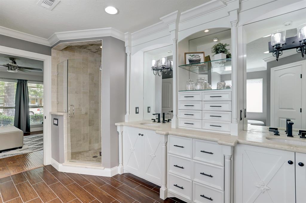 Dual vanities with so much other storage for your stuff! Showcases the custom cabinets, wood-look tile, marble countertops, and tumbled marble shower.