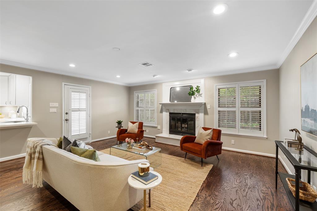 The spacious living room features wood floors, crown molding, recessed lights and plantation shutters.