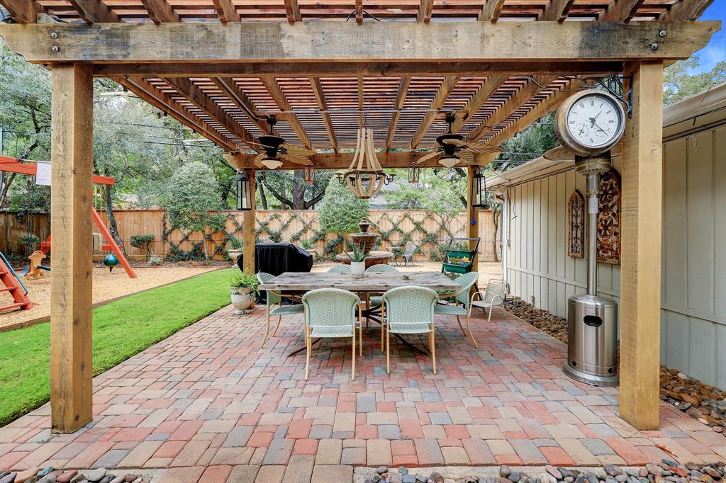A trellis covered paver patio is complete with ceiling fans and a chandelier, as well as a working fountain at the far end.
