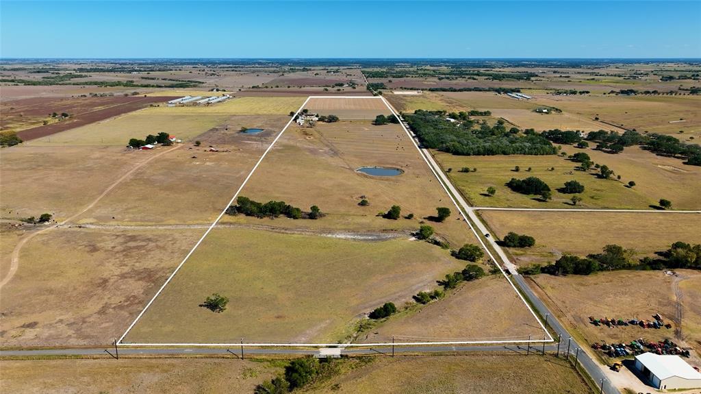 Beautiful country farm outside of Shiner, with approx. 5900 sq ft of road frontage.  If you've been looking for the perfect farm in the perfect town, here it is. The home is 3497 sq ft (LCAD) home with 5 bedrooms and 3 full baths. It is sure to be the place you'll retreat to, to get away from it all. This country home provides comfortable accommodations featuring an open floor plan, kitchen with lots of cabinetry, spacious living room with wood burning fireplace, primary bedroom with en suite bathroom, additional bonus room/utility room, carport, and covered outdoor cooking area. The property is mostly open w/ gently rolling terrain, creek, and two stock ponds. The property has barns and sheds ideal for storing farm equipment, working pens, and cross fencing ready for cattle.