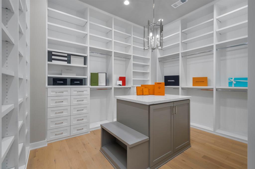 The wardrobe closet has a polished marble packing island with a leathered finish. Along with an abundance of storage drawers along the back wall, you will also find additional storage in the center island.  Not captured in this photograph is a wall of adjustable-height shelves to store an immense number of footwear.