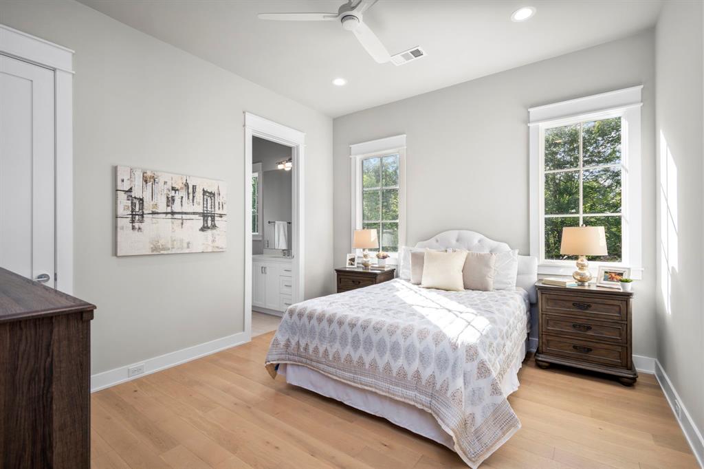 This secondary bedroom is located on the west side of the home. This room measures 13 1/2' x 12' and has west facing windows. In the far left corner of this image is a doorway leading to the large, walk-in closet.  The doorway adjacent to the bed leads to the ensuite bath.