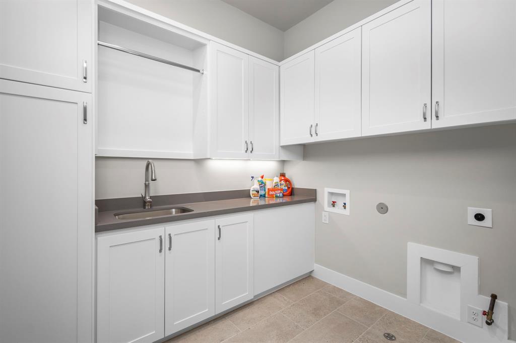 One last amenity on the second floor of this home is the 9 1/2' x 7' laundry room. A single basin wash sink with a drip rod above is to the left while a quartz counter acts as the perfect folding table.
