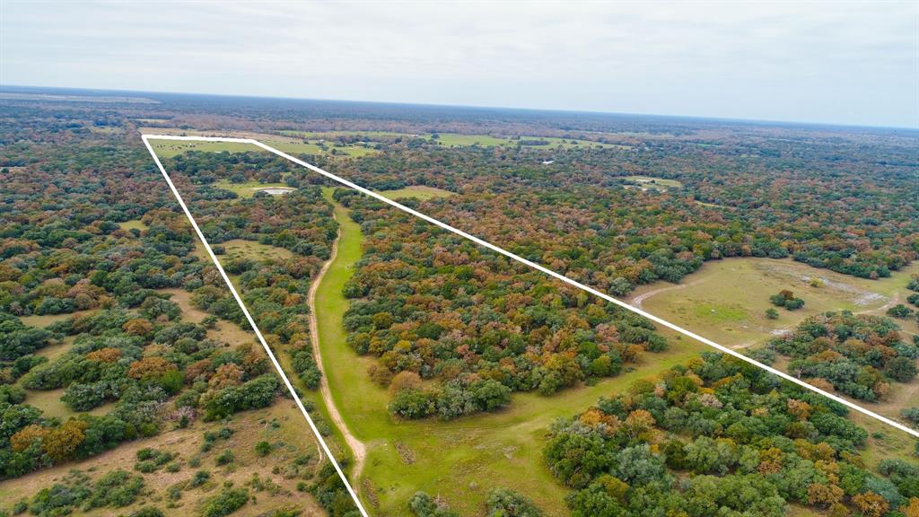 Under 100 acres with a move-in-ready home. Located on FM 530 in Hallettsville find the dream combination of open grazing areas as well as wooded areas totaling 94.68 acres. This long tract is great for hunters, full-time living, or just a weekend getaway.  The property has mature oaks, post oaks, and pecan trees as well as two ponds.  The 1,605 square foot, 3 bedroom, 2 bath home has enough room for everyone. Containing a large gathering room, fully equipped kitchen, and dining room with beautiful windows and views, the home is truly a retreat.  In addition to the scenic views from the inside, the home has a covered porch at the front and back of the home.  There is room to park 2 cars under the covered carport along with your ATV/Ranger.  Included on the property is a Morgan building just outside the house that has been finished out with bunk beds, window A/C and a sink for additional sleeping space.