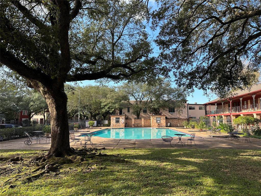Community pool is large and spacious with shade tree and patio furniture