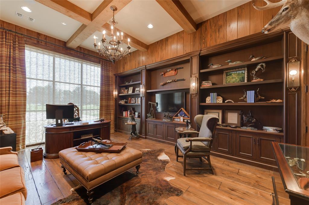 The generously sized STUDY (20 X 15) includes wood paneled walls, hardwood flooring, wood blocked ceiling with hanging glass/metal chandelier and recessed lighting, built-in book shelves with cabinets below, metal framed windows with Roman shades/drapery, TV niche, walk-in closet with built-in filing cabinets/drawers/4 metal/glass light sconces along shelving, metal framed windowed wall with Roman shades and custom drapery, en suite bath.