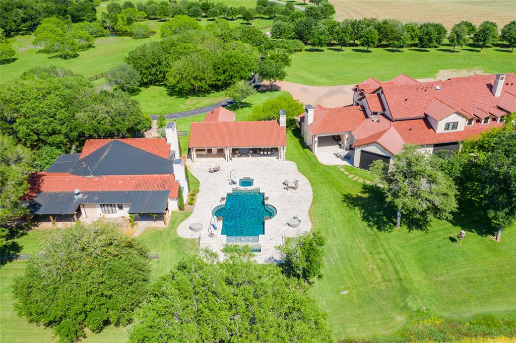 View of the guest and main houses situated on both sides of the complex\'s heated/over-sized pool with infinity edge/water features/hot tub, fire pit and covered outdoor kitchen and dining areas - all surrounded by  open pasture areas with native Pecan/Mixed Oak/Mesquite trees!