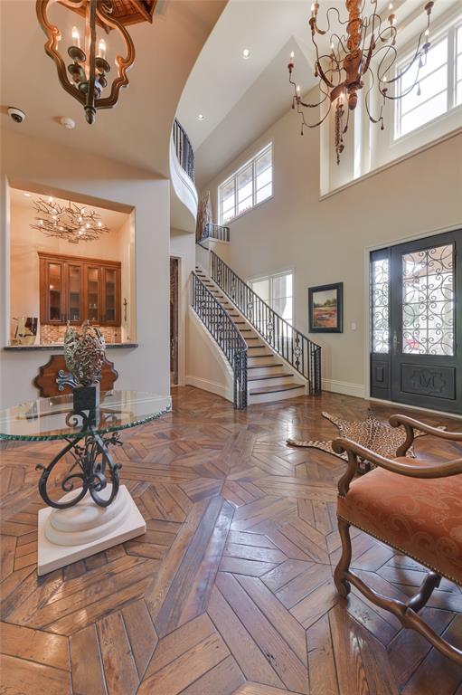 A handsomely appointed and brightly lit two story FRONT ENTRY (18 X 13) is welcoming with its 2nd level windows with two light sconces, metal/wood chandelier, textured/painted walls, staircase (painted risers/wood treads/iron railing) to 2nd floor landing, hanging wood/metal chandelier, patterned wood flooring. The Entry Foyer gives access to the fully equipped and elegantly designed WET BAR and nearby WINE ROOM.