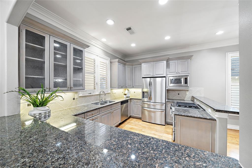 The kitchen is fitted with under-the-cabinet lighting that illuminates the extensive granite countertops. The stainless steel appliances perfectly complement countertops, creating a cohesive and stylish design.