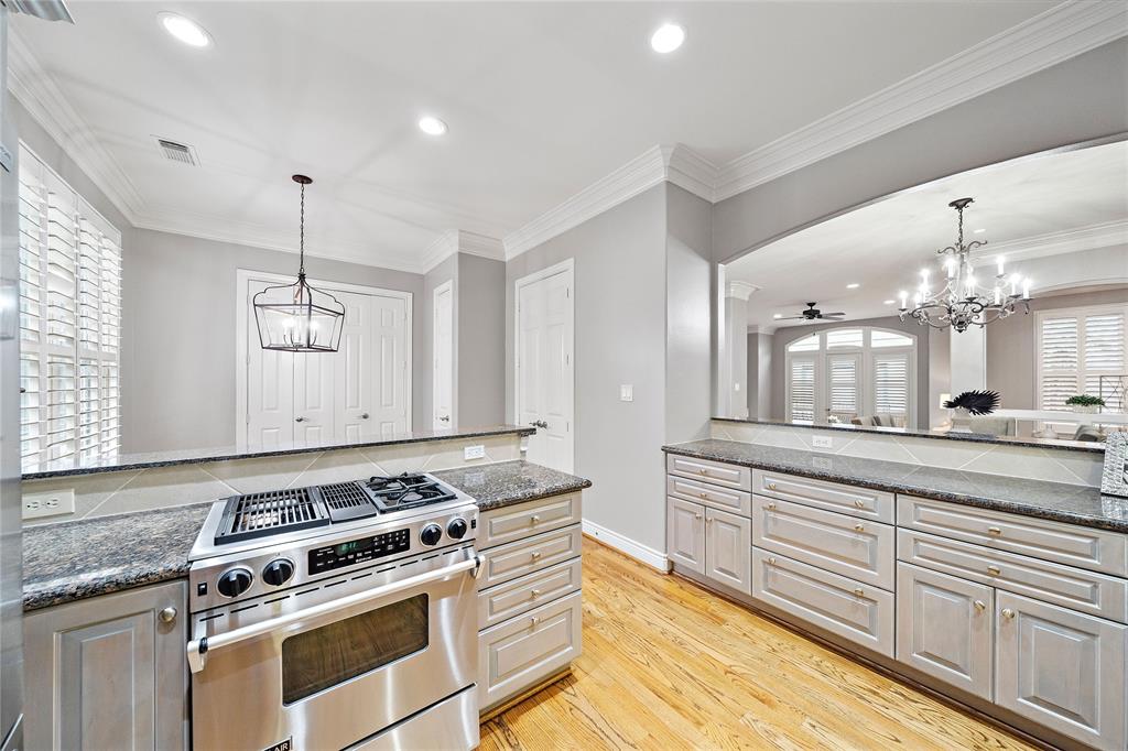 The kitchen features a stainless steel gas cooktop, spacious granite countertops, and added storage options from the adjacent laundry/utility room and extra closet space.