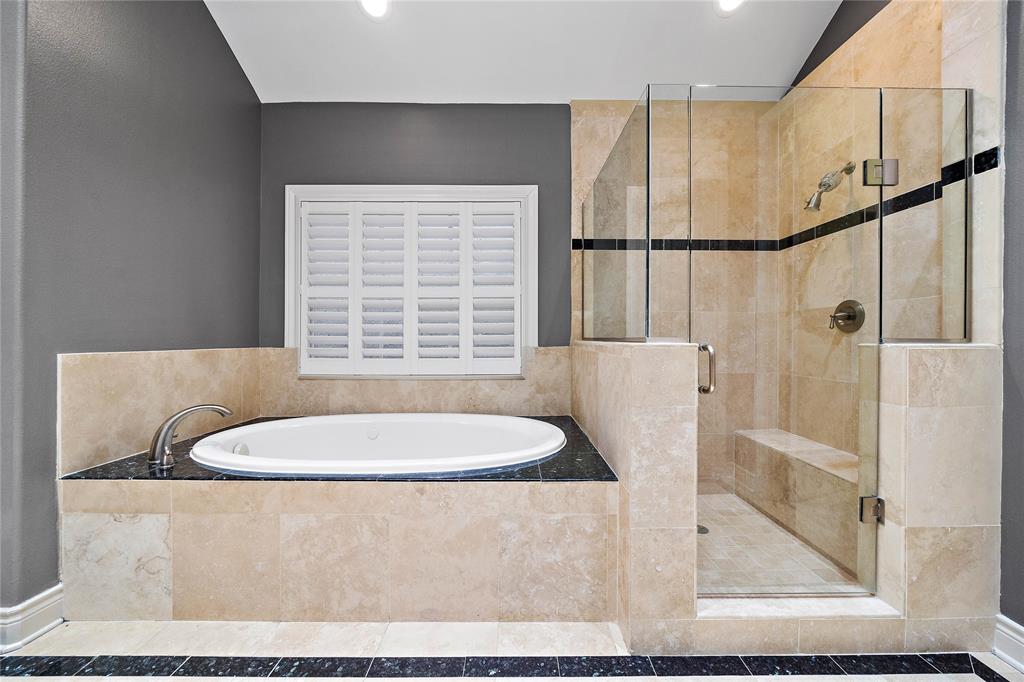 Perfect for unwinding, the primary ensuite bath comes complete with a glass-enclosed shower and a jetted tub with tile surround.