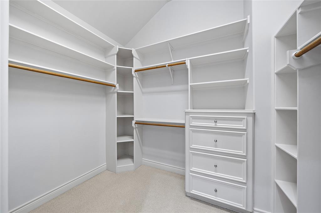 Enjoy ample storage in the spacious walk-in closet, featuring coat racks, built-in shelves, and cabinets that provide an organized space for all your needs.