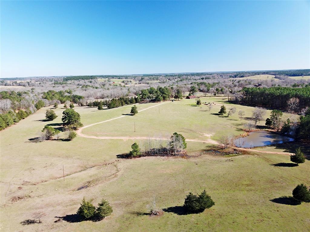 This 92.65-acre property offers scenic rolling terrain, great home-sites with scenic views, and a favorable mixture of pastureland and forestland. The property is suitable for a private ranch or homestead or can be your getaway destination to relax and enjoy the East Texas scenery. Much of the land is open native pastures, with approximately 20 acres being forested, part of which consist of 30+ year pine plantation, with the balance in native forested drainage areas. The property features three tanks ranging from 3/10 acre to approximately 1.5 acres in size, all serving as a livestock resource and great attraction for wildlife. The property features an approximately 1,512 SQFT home towards the eastern portion of the property. The home is a 4-bedroom two bath brick structure, with a metal roof, and open porches on the front and rear of the home. The exact age of construction is uncertain but believed to be in the era of 1954.