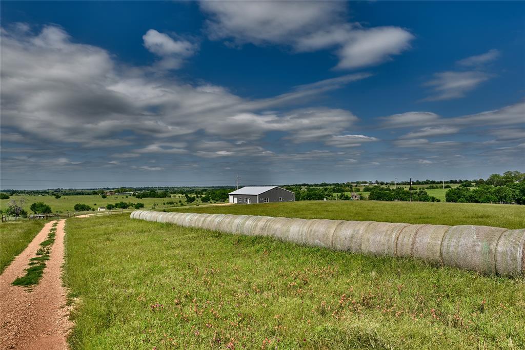 2022 Custom Barndo set amid the rolling hills of New Ulm, TX! This relaxing retreat has all the bells & whistles you want in a home, approximately 1250 SF (25 X 50) of shop space with three roll up doors w/plenty of room for your Texas size truck & trailer w/bonus 1/2 bath, beautiful views of the rolling hills & starry nights. Modern farmhouse home features a gorgeous country kitchen w/butcher block countertops, seating of 6 at eat at island (quartz countertop on the island), soft close cabinetry, GE appliances, large pantry and open to the living room. Soaring 21’ ceilings in the living room welcome you to unwind & relax while feeling open & airy. Split plan features a private primary rm w/modern ensuite – you will love the lg shower, soaking tub & spacious closet.  3 additional bedrooms, 3 full bathrooms in the home and a ½ bath in the shop!  Utility room is conveniently located near the center of the home.  10.17 acres, Pond, 3 Pastures for your livestock & perimeter field fencing.