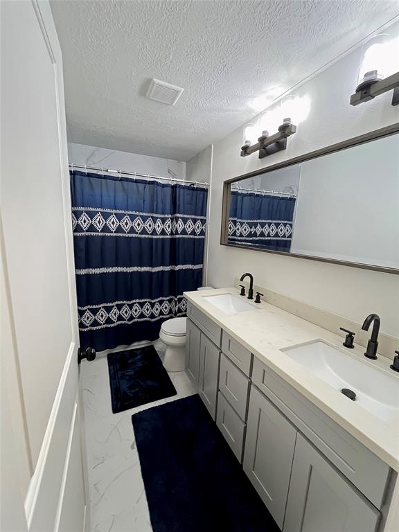 Secondary bathroom with double sinks, great lighting, and tub/shower combo