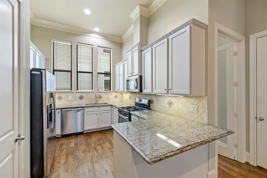 The open kitchen with granite countertops, stone backsplash, shaker-style cabinetry, and large pantry is perfect for home chefs