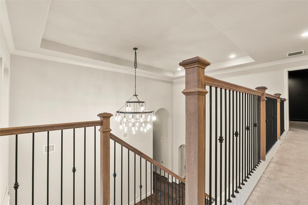 Beautiful bannister and a view of the custom oversized chandelier in the formal dining room.