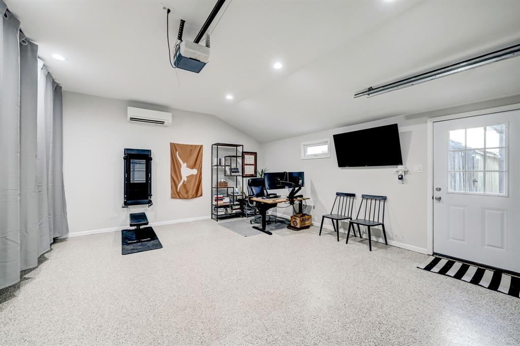 The garage has been fully finished out including epoxy flooring and an installed air conditioning unit, to be creatively used as additional home office and workout space.  The heavy curtain to the left hides space being used for storage.