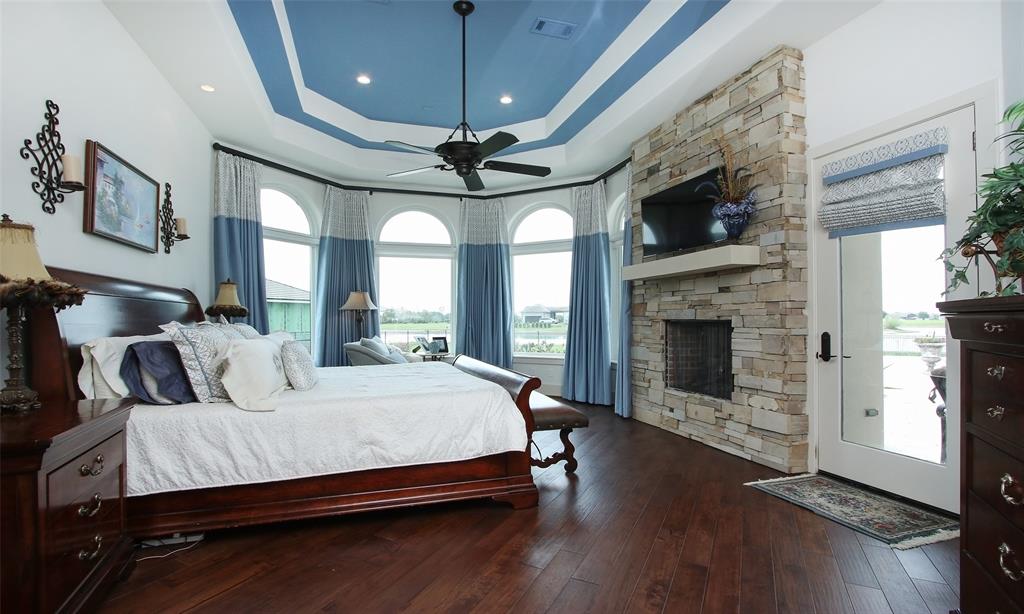 A stunner of a master suite!  Everything from the floors to the ceilings are dreamy.  Lovely stone fireplace is the centerpiece with door leading to pool area.