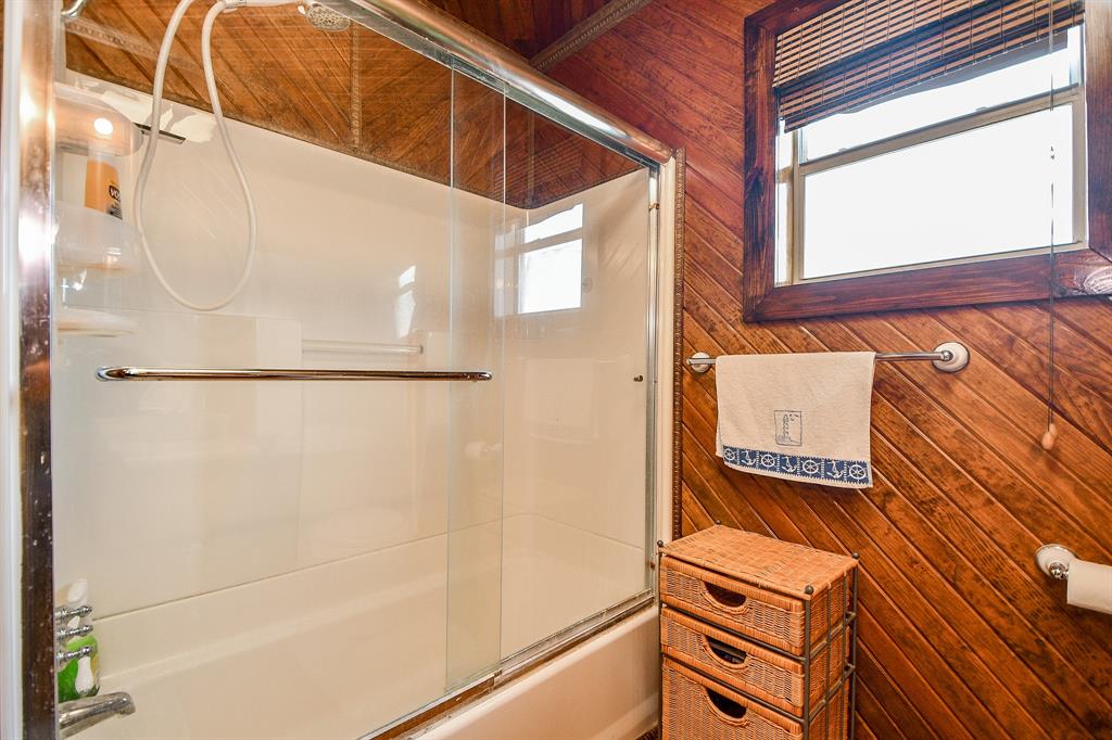 The bright, spotless combined bathtub/shower sits behind clear, sliding glass doors.