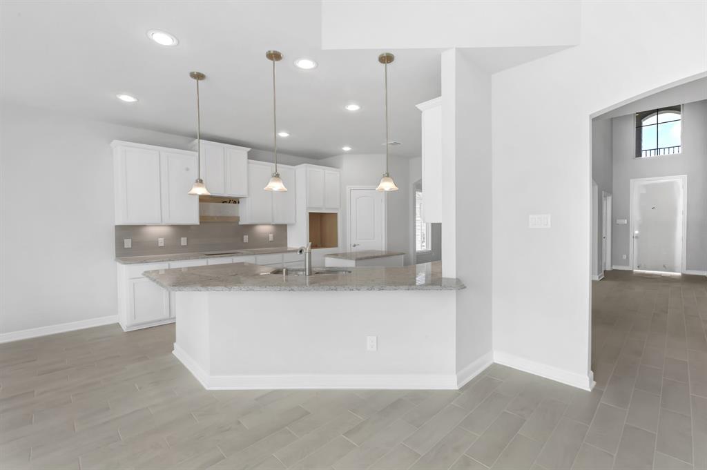 This kitchen is by far any chef’s dream! This spacious kitchen features high ceilings, white stained wood cabinets, granite countertops, SS appliances, modern tile backsplash, recessed lighting with additional custom pendant lighting, extended counter space, granite kitchen island with double sink and space for breakfast bar, and a walk-in pantry all overlooking your huge family room.