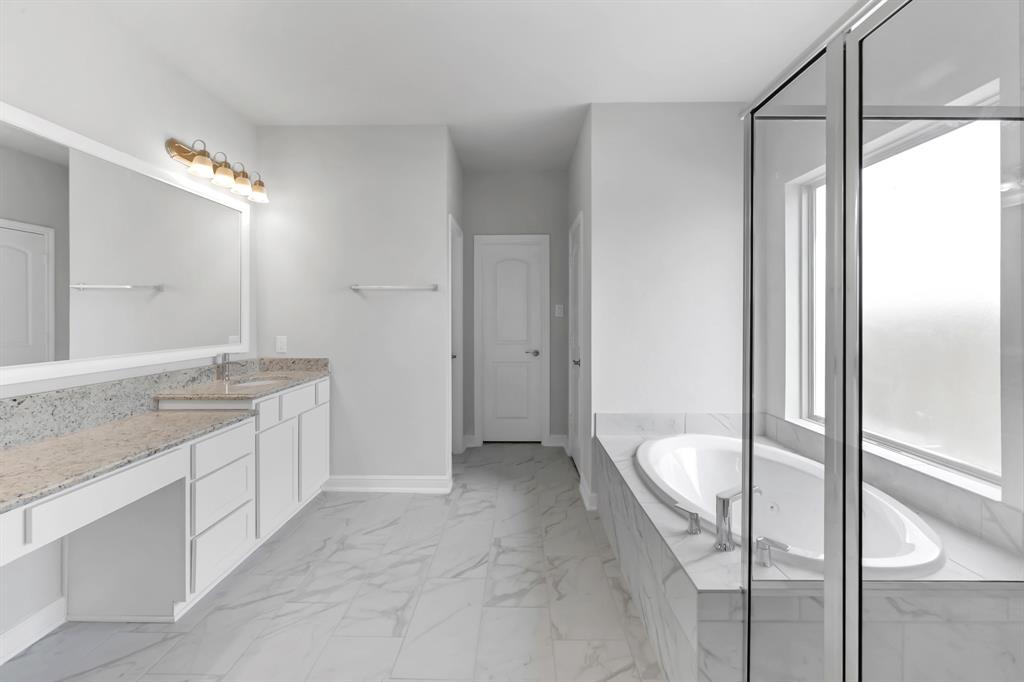 This primary bathroom is definitely move-in ready! Featuring a walk-in shower with tile surround, separate garden tub for soaking after a long day with custom tile detailing, white stained cabinets with light countertops, spacious walk-in closet with shelving, high ceilings, custom paint, sleek and dark modern finishes.