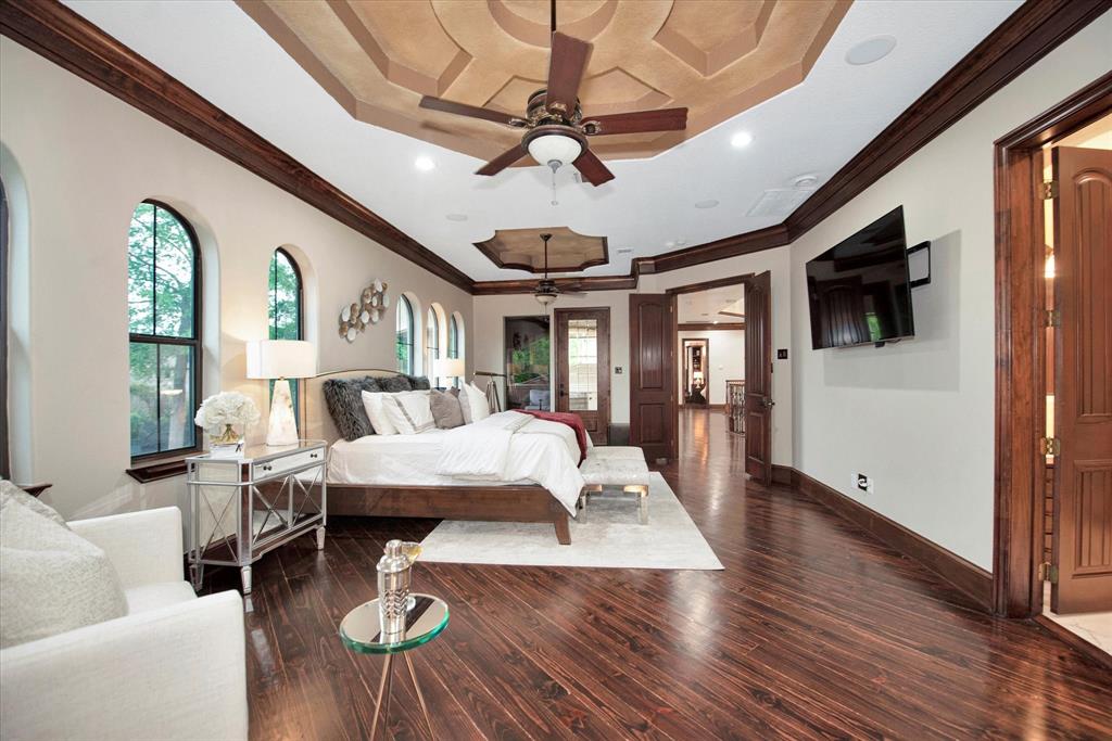 This primary bedroom features soaring high ceilings, private access to a balcony overlooking the 2 acre estate and a fireplace.
