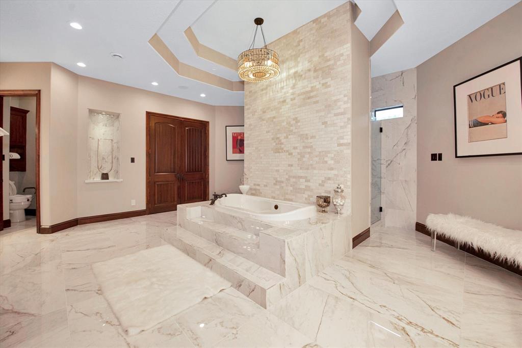 The primary bathroom features a large soaking tub, walkthrough shower, separate double vanities and a fireplace.