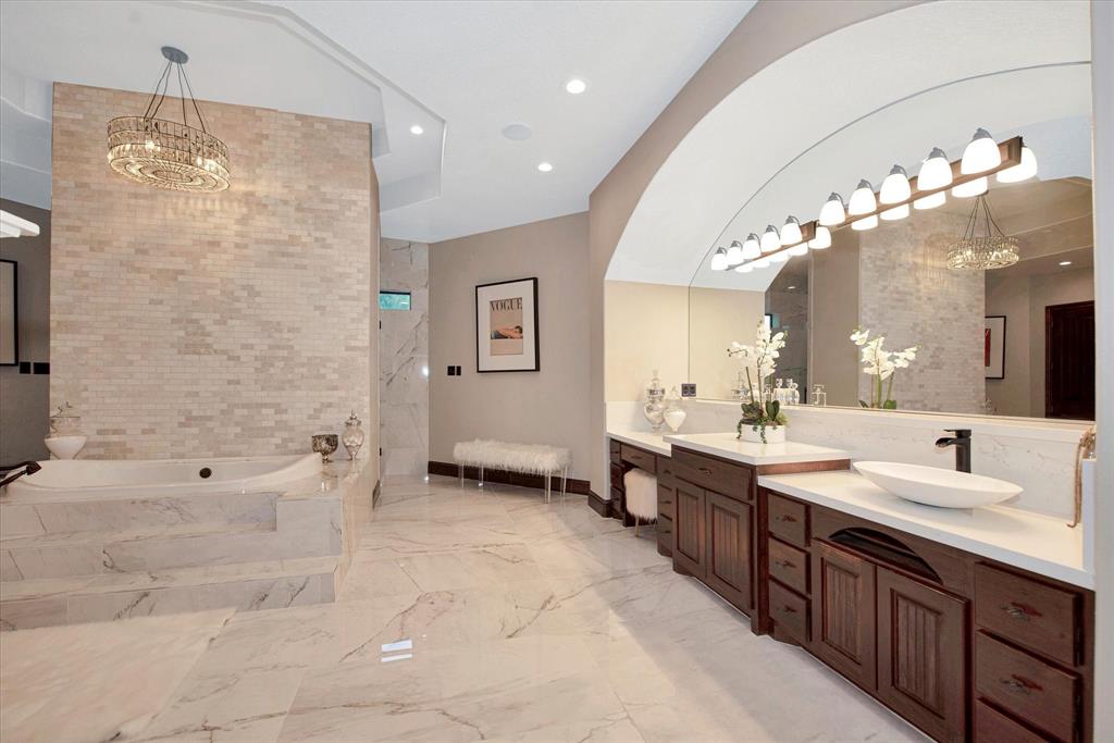 The primary bathroom features a large soaking tub, walkthrough shower, separate double vanities and a fireplace.