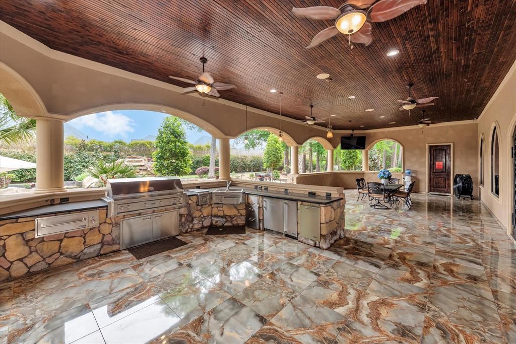 Large outdoor kitchen with bar and dining area overlooking the estate.
