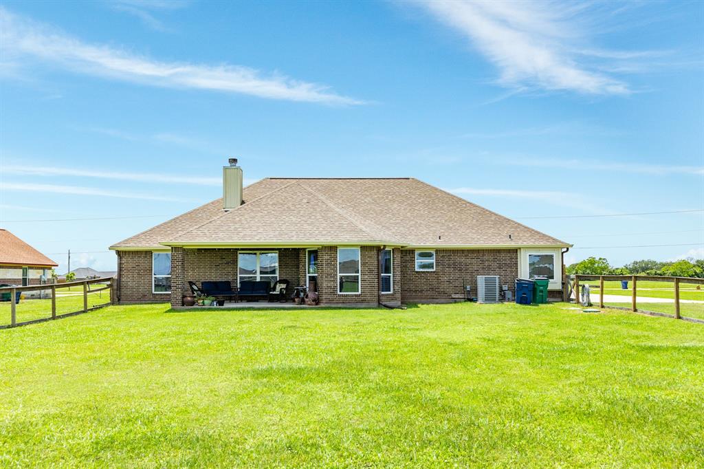 Back view of home has fenced area for pets and additional dirt work and poured concrete.