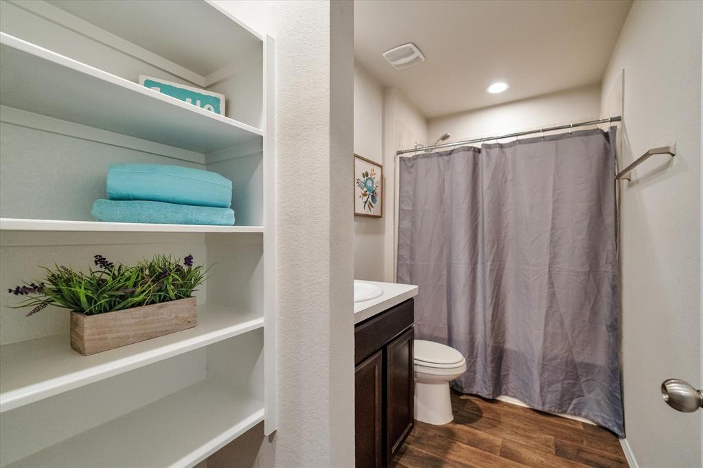 2nd full bath wit build-in shelving and dark cabinets.