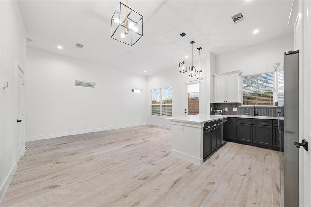 Adjacent to the living area, the kitchen flaunts vibrant pendant lights, quartz countertops, multiple built-ins, and a breakfast bar offering additional/informal dining space.