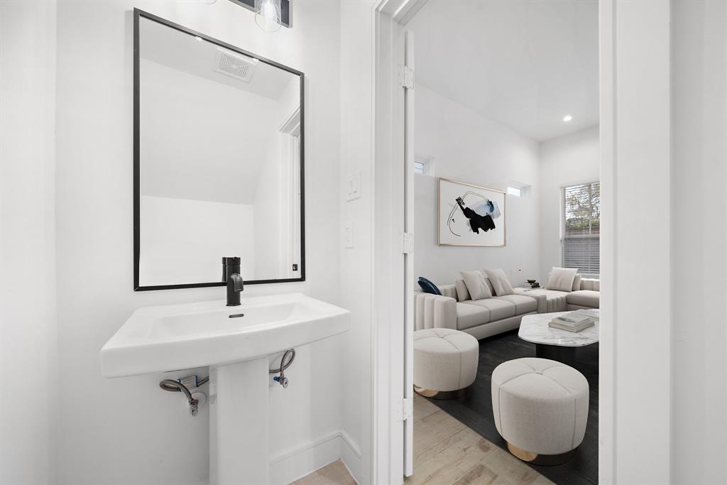 Right off the living area, find a formal half-bath that features stylish vanity lights and a tall mirror, creating the perfect space for quick refreshes or pampering.