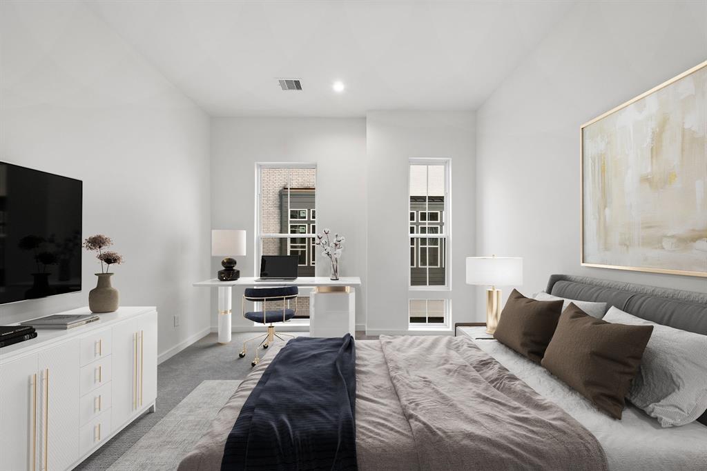 This secondary bedroom features plush carpeting, tall single-hung windows, and ample space for a large bed, a desk area, and a dresser.