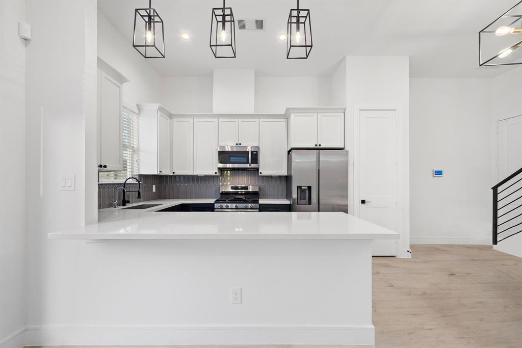 The kitchen is fitted with modern features, including top-of-the-line Samsung appliances, a spacious pantry, and multiple built-in cabinets for extra storage. The spacious quartz island provides ample room for meal prep and counter seating. Stylish pendant lights and a custom backsplash adorn this great culinary space, creating a tasteful ambiance.