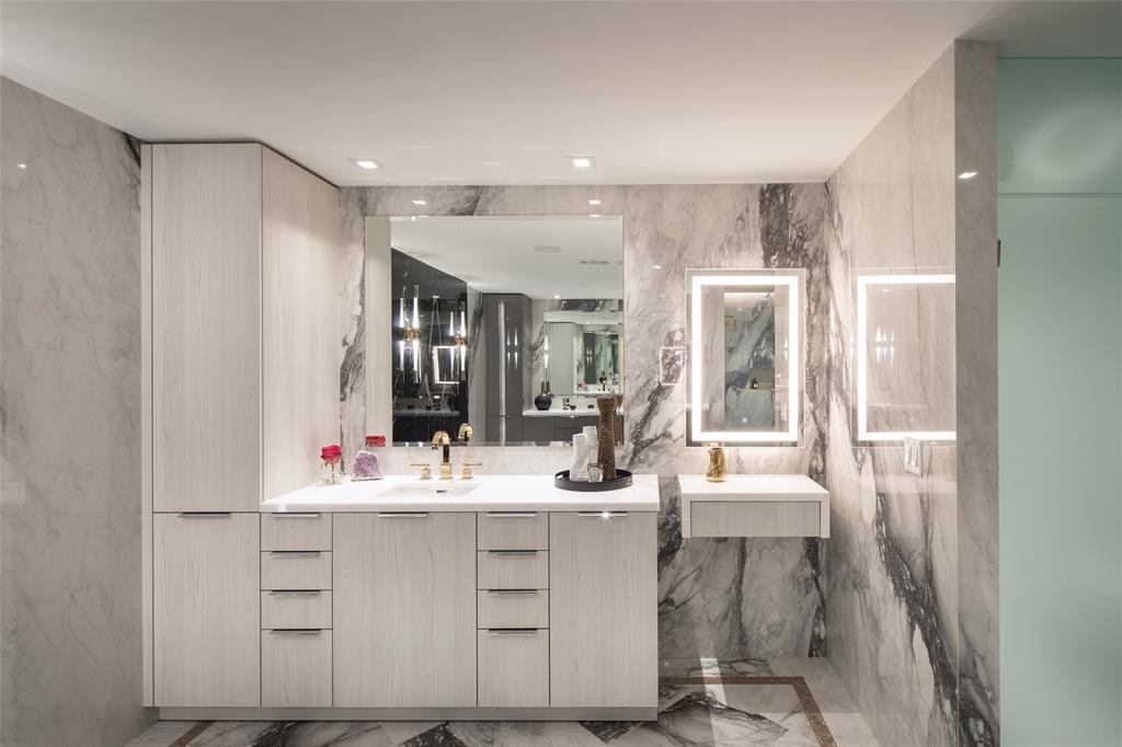 Secondary bathroom offers marble, gold finishes, and a built in vanity.